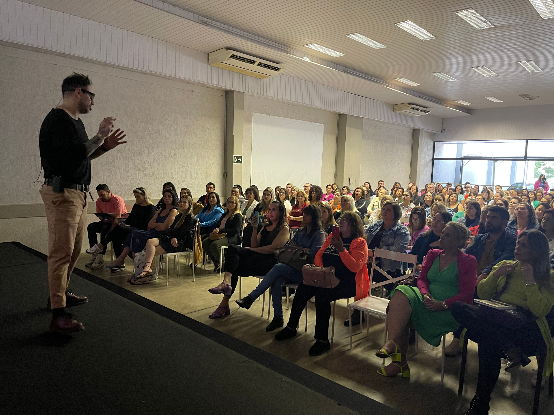 Max Daguano conduzindo palestra próxima ao público em workshop presencial