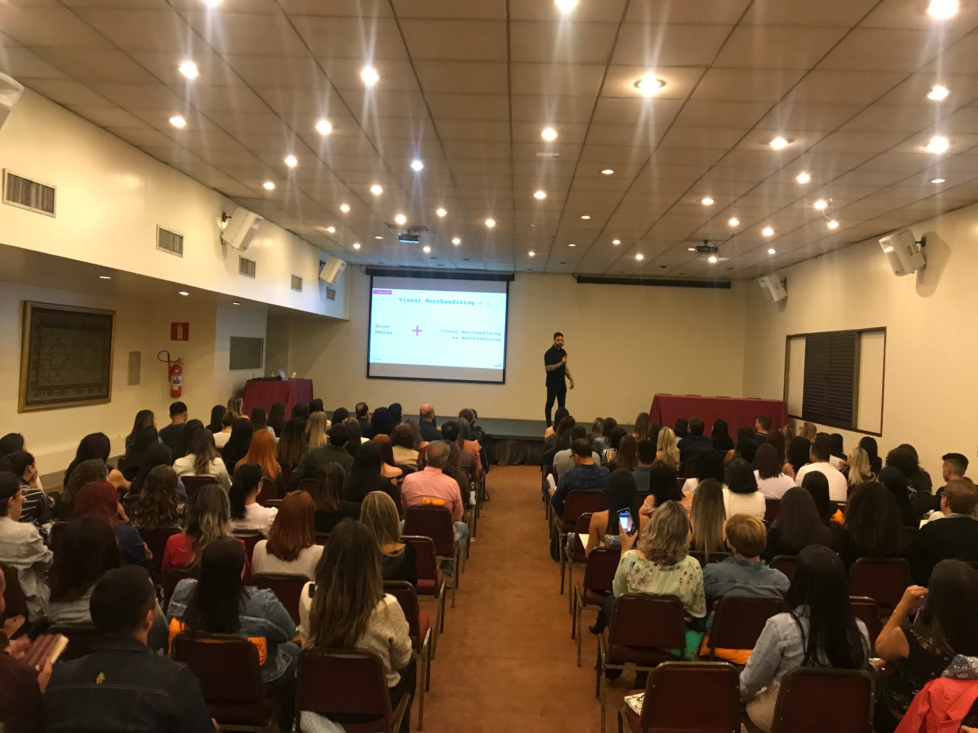 Max Daguano palestrando para auditório lotado em evento de varejo